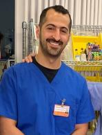 man smiling while wearing blue scrubs