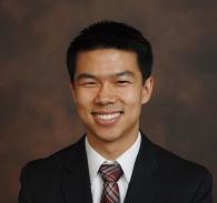 man wearing a suit smiling against a brown background