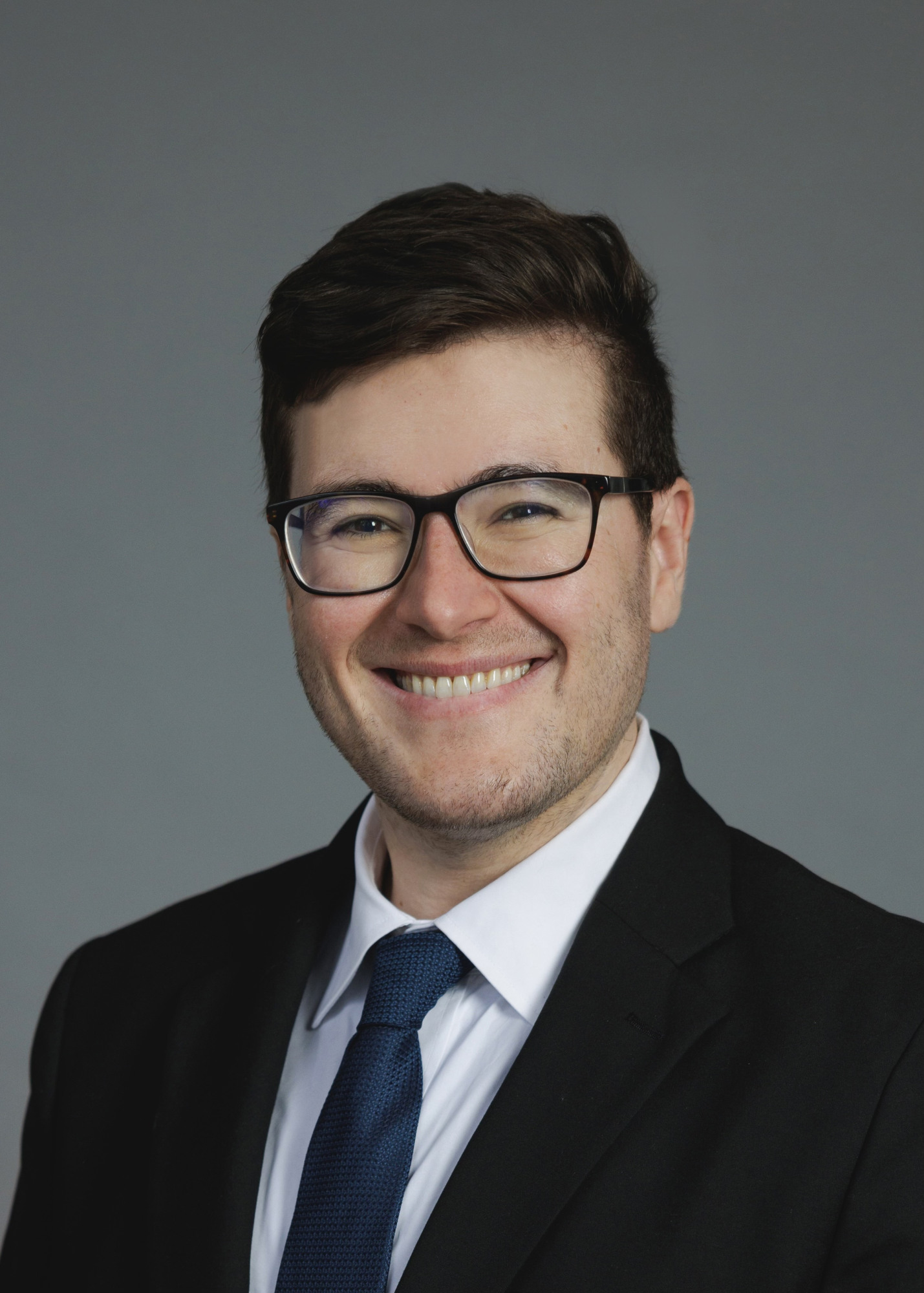 smiling man with brown hair wearing a suit