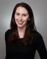 woman smiling wearing a black shirt against a grey background