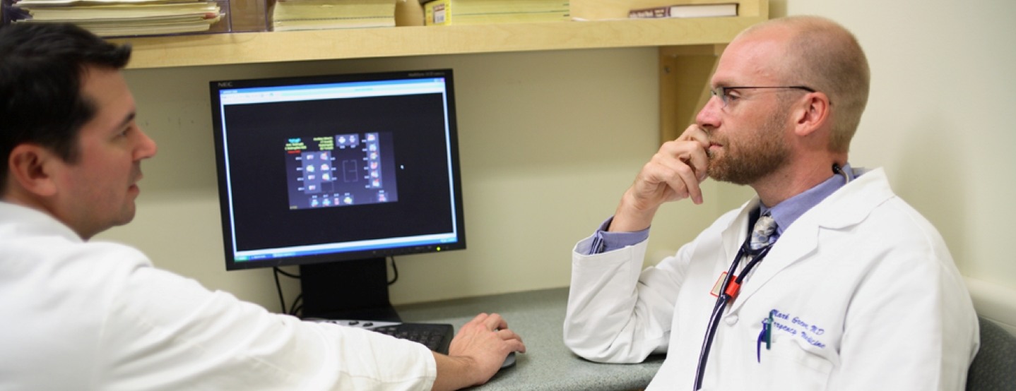 two doctors wearing lab coats sitting at a computer
