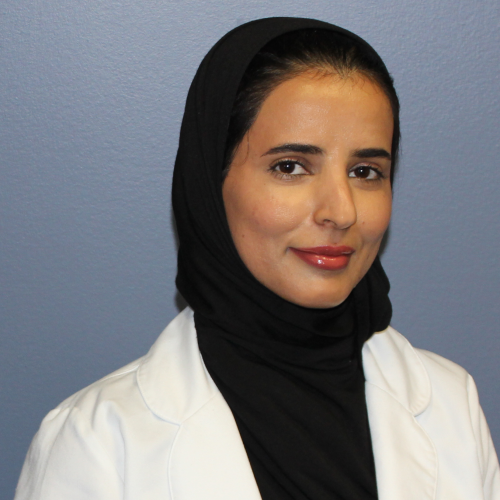 woman smiling wearing a hijab and a lab coat
