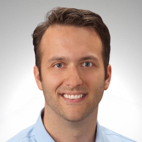 headshot photo of a man man smiling with a grey background