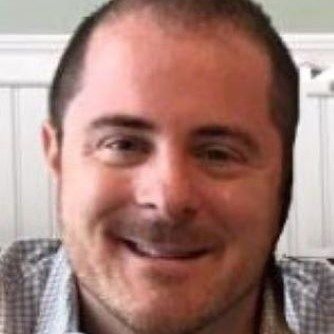 physician smiling wearing a grey button up shirt