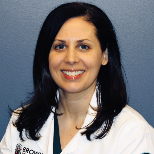 physician smiling wearing a lab coat against a blue background