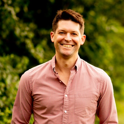 man smiling with rust colored button down shirt