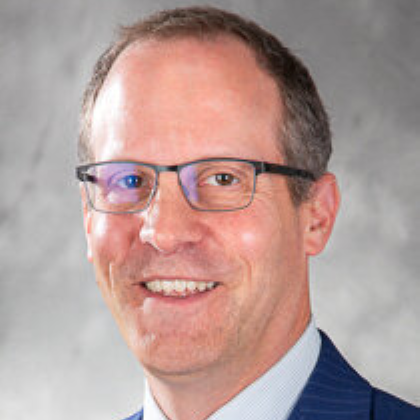 man with glasses wearing a blue suit and tie