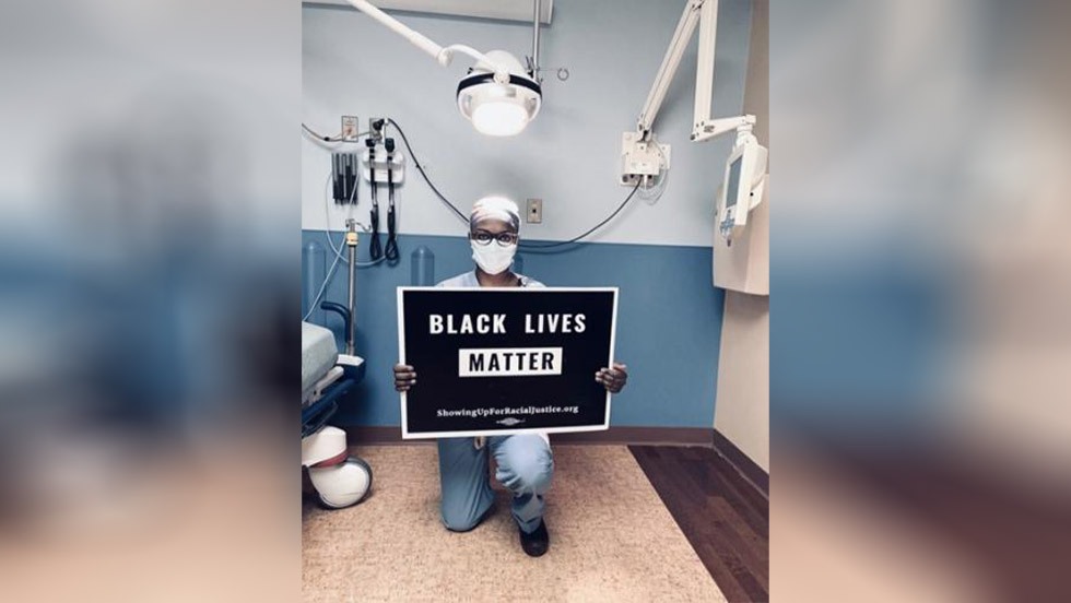 person kneeling with a Black Lives Matter sign