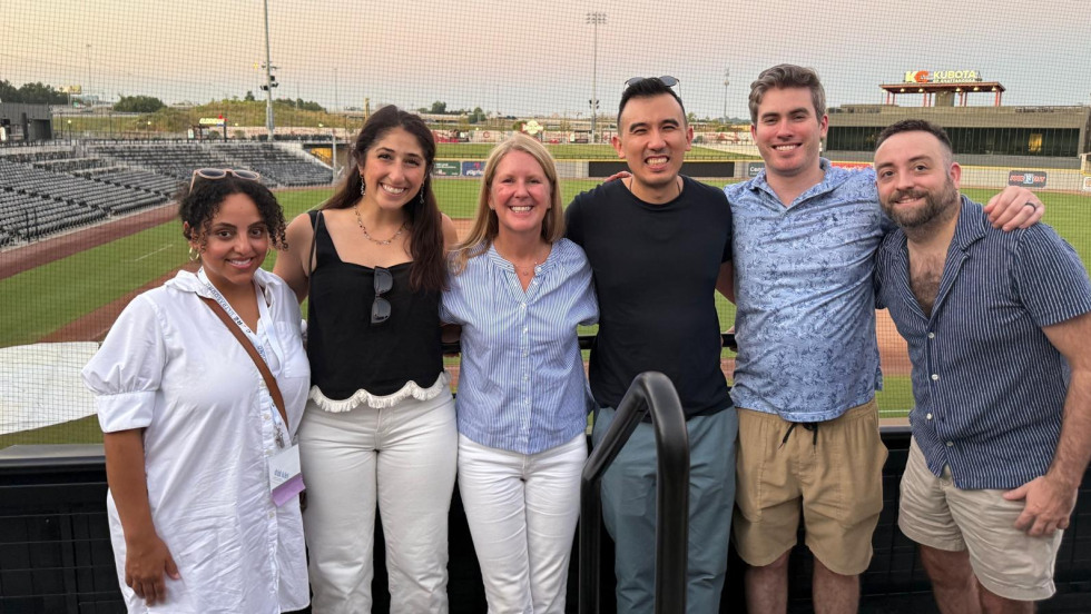 group of people standing with a ball field behind them